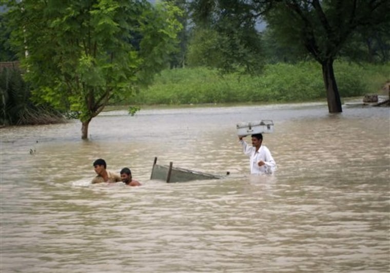 Pakistani villagers pull their belongings through deep floodwaters on the outskirt of Dera Ghazi Khan, Pakistan on Wednesday, Aug. 4. This year's monsoon season has prompted the worst flooding in Pakistan in living memory and already killed more than 1,500 people, official said. 